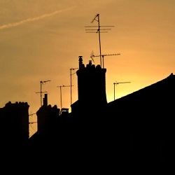 Rooftops, chimneys, and antennas at sunset