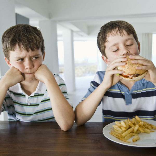 envious boy watching another boy eat