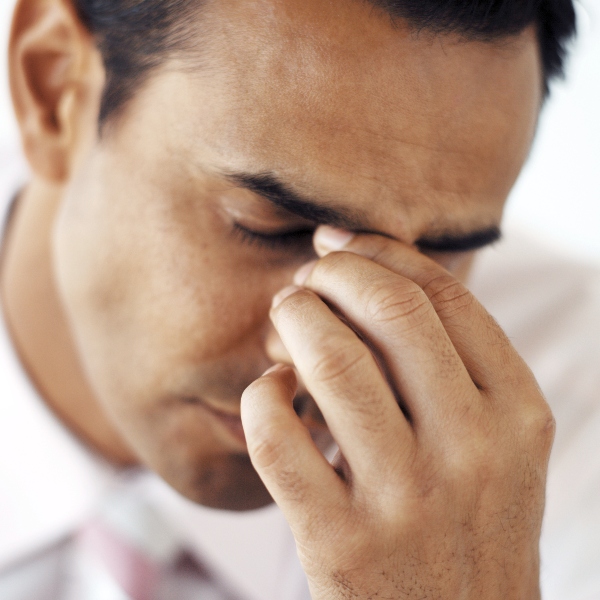 Close-up of a young businessman holding the bridge of his nose