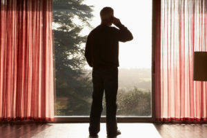 Rear view image of mature adult with short hair making phone call in empty living room