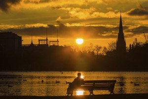 Silhouette of man sitting on a park bench at sunset