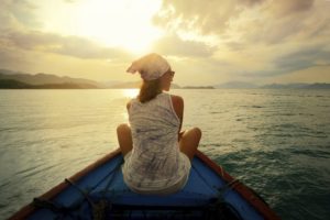 A woman travelling by boat at sunset