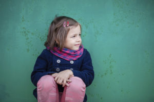 Portrait of preschooler girl sitting near wall