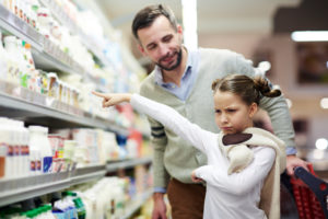 Child and parent grocery shop while child is upset over not getting requested item
