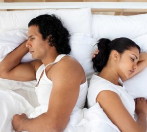 Upset couple in bed sleeping separately