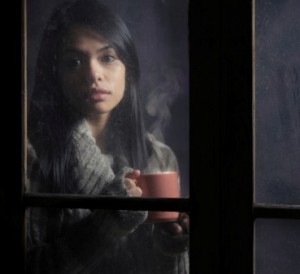 woman behind window with a cup of coffee