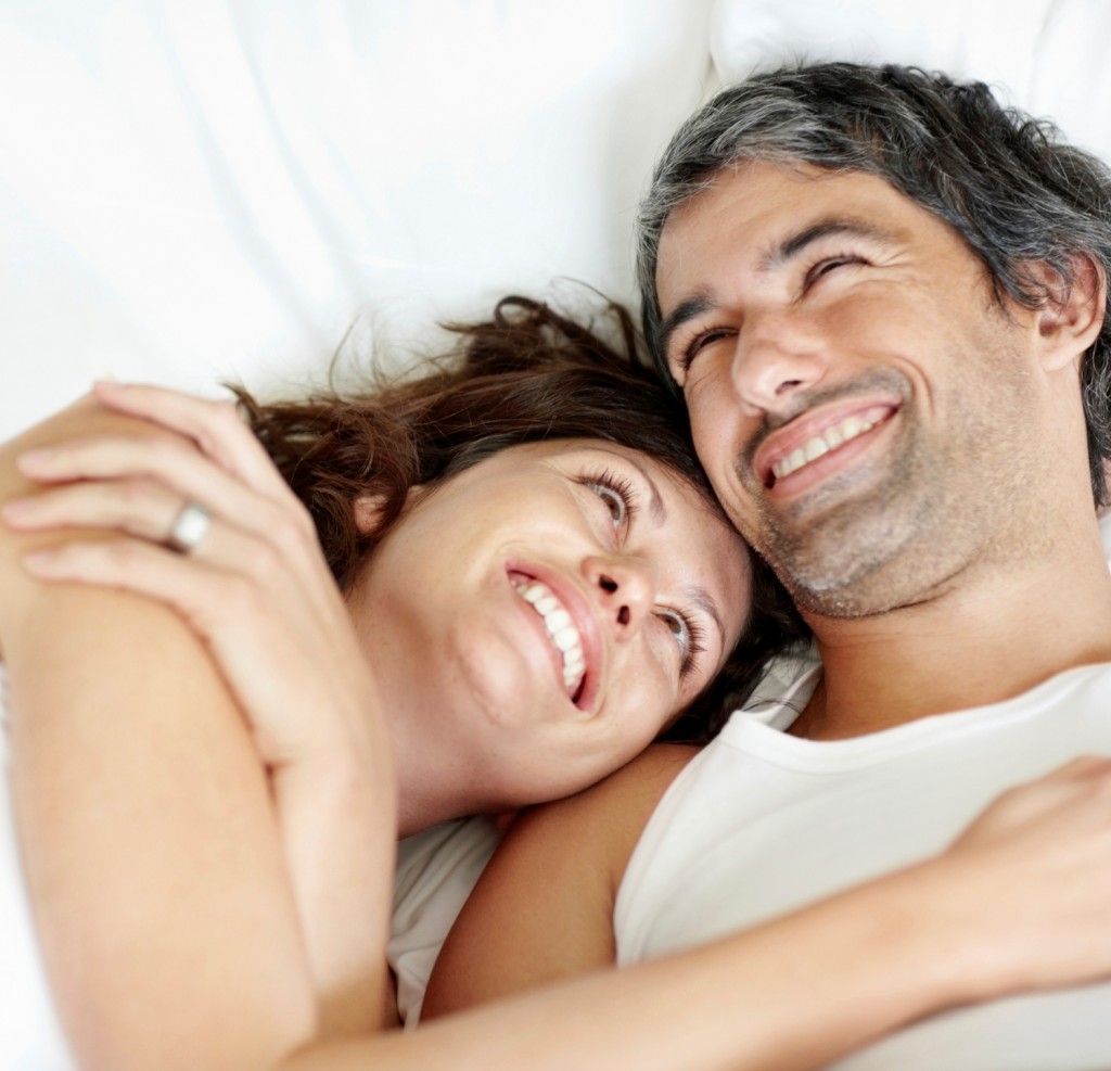 Cosy mature couple lying in bed smiling
