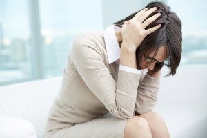 An exhausted woman holds her head in her hands