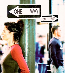 side profile close-up of a woman leaning on a signpost on a sidewalk