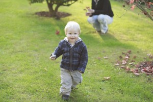 A toddler runs while his parent watches
