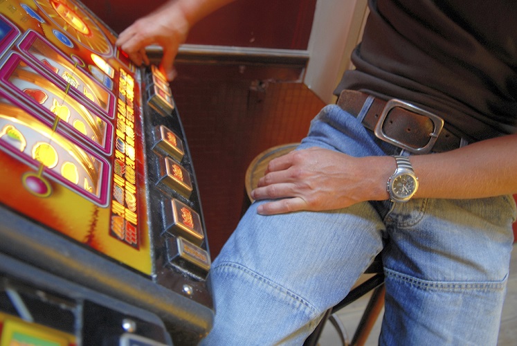 Mid section view of a man playing on a slot machine in a casino