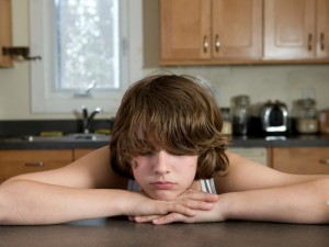 teen rests chin on layered hands on kitchen counter