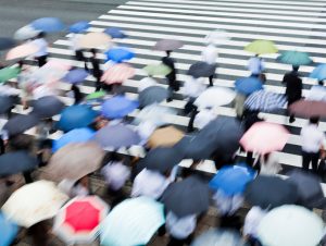 people with umbrellas waiting to cross street