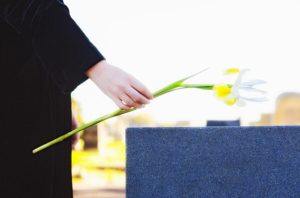 Woman's hand leaving flower on tombstone