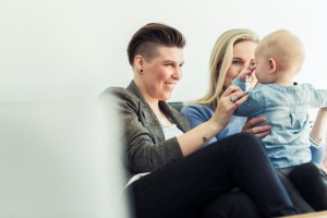 Young mothers playing with baby on sofa