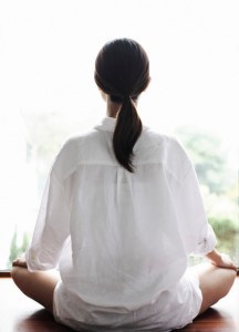 Meditating woman facing away from the camera