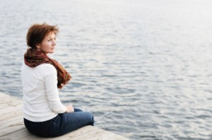 Woman sitting on wood boards by the water