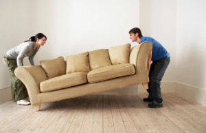 Two people moving a sofa together