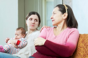 Adult daughter holds baby on lap, places hand on shoulder of mother