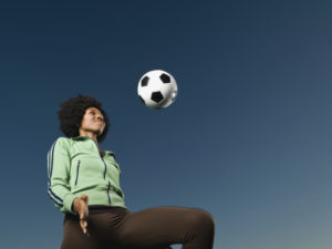 African woman kneeing soccer ball