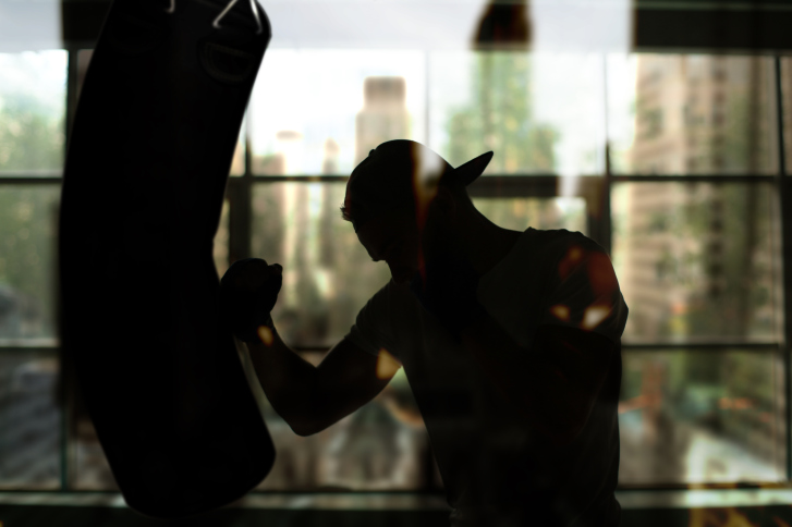 Silhouette of man hitting a punching bag
