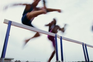 athletes jumping over hurdles