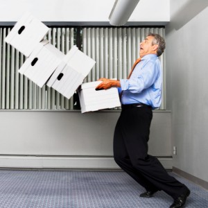 Businessman drops stack of four boxes in small office