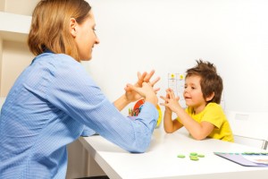 Boy exercises putting fingers with therapist