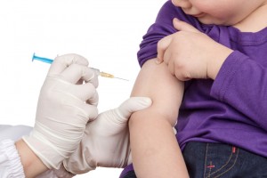 Child raises sleeve of shirt as doctor administers vaccine