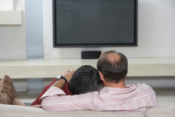 Couple Sitting on Sofa with Television Off