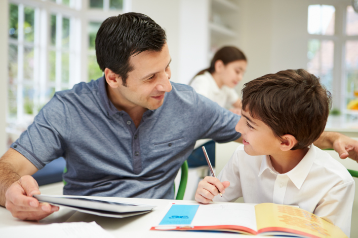 Father Helping Son With Homework Using Digital Tablet