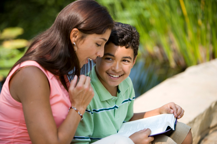 Young woman sitting with her son reading book