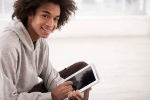 Young man looks up smiling from tablet pc