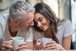 Close up portrait of a cute young caucasian blonde couple trying to kiss  where man is holding his girlfriend face in his hands close outside while  dating. Stock Photo