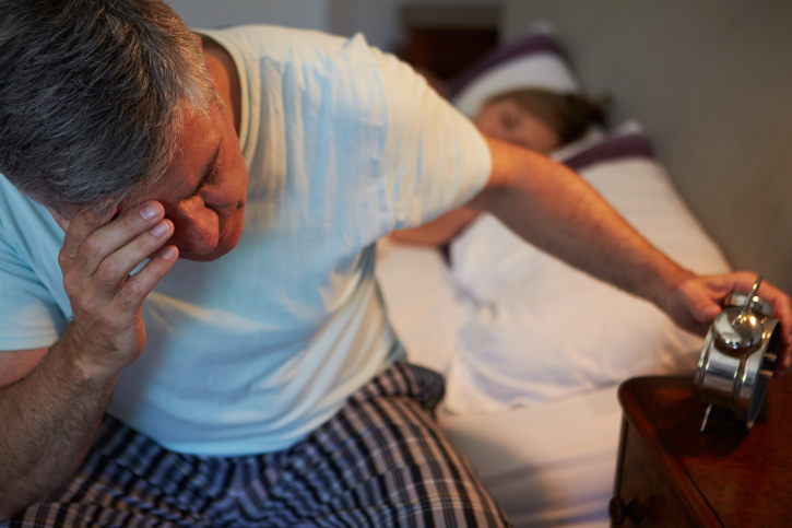 A man sits in bed after a sleepless night