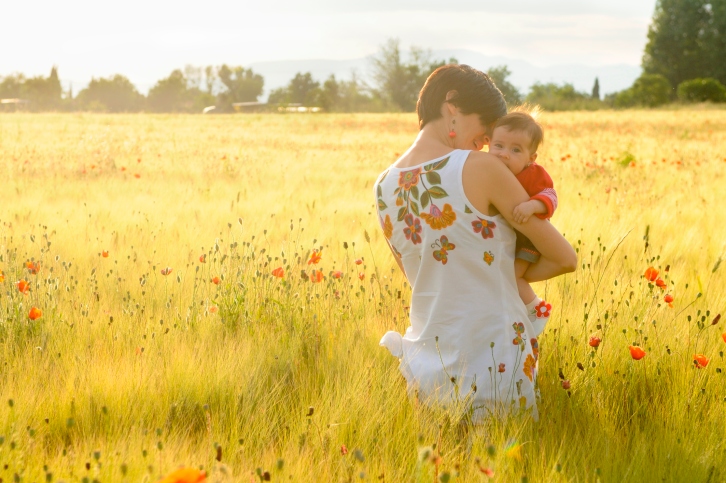 Mother holds a baby in a field of poppies