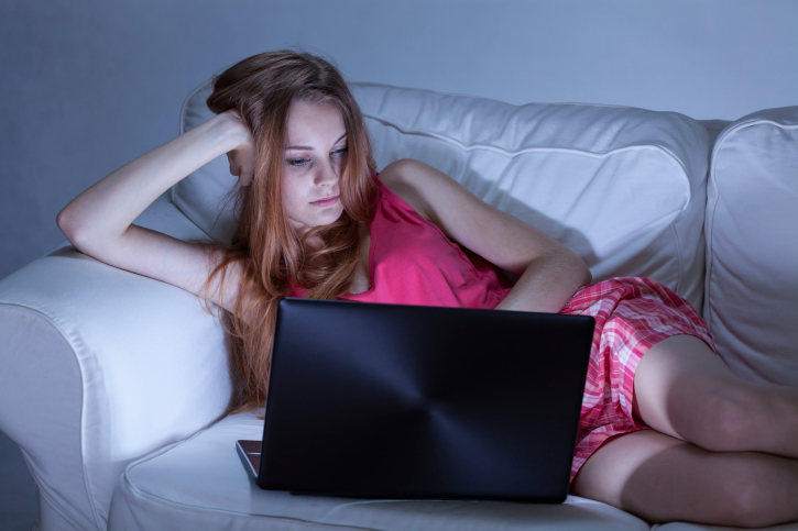 Teen girl using laptop on couch at night