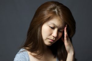 Asian woman with headache thinking