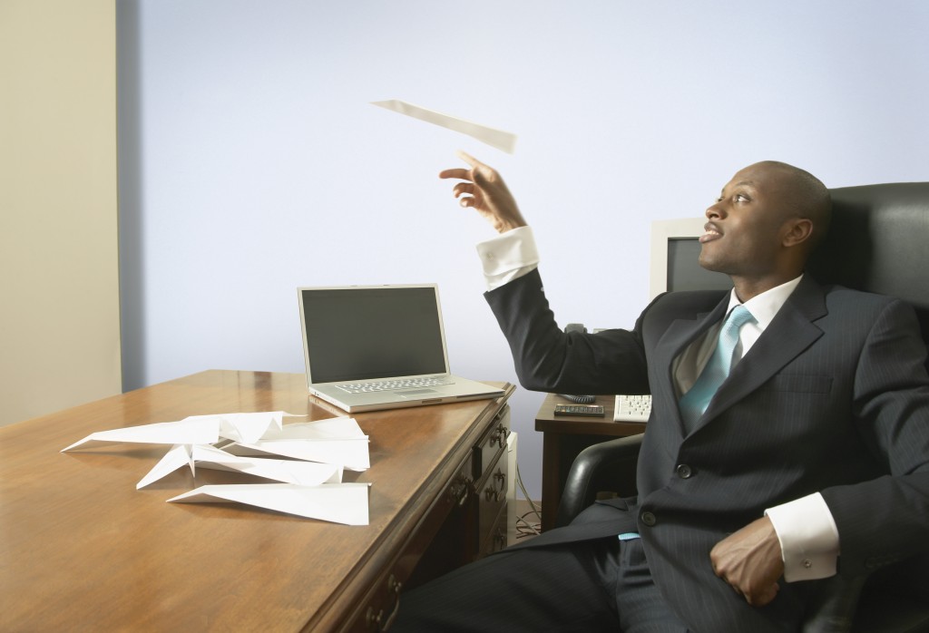 Man procrastinates at his desk at work.