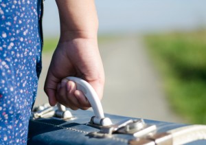 Refugee girl carrying suitcase down road
