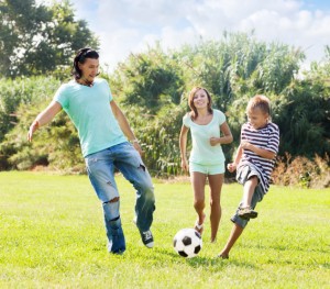 Middle-aged couple and teenager playing with soccer ball