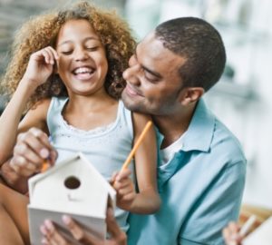 Parent and child paint birdhouse together. Both h...