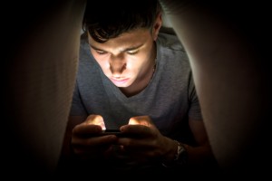 Teenage boy hiding while using a mobile phone
