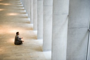 Businessman sitting in yoga pose on floor of lobby