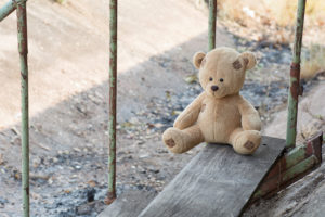 Photo of stuffed bear resting alone on wooden steps outside