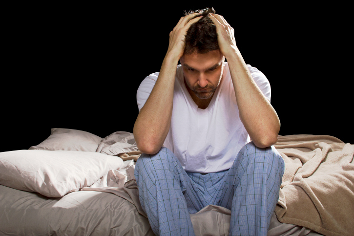 Man sitting up in bed unable to sleep