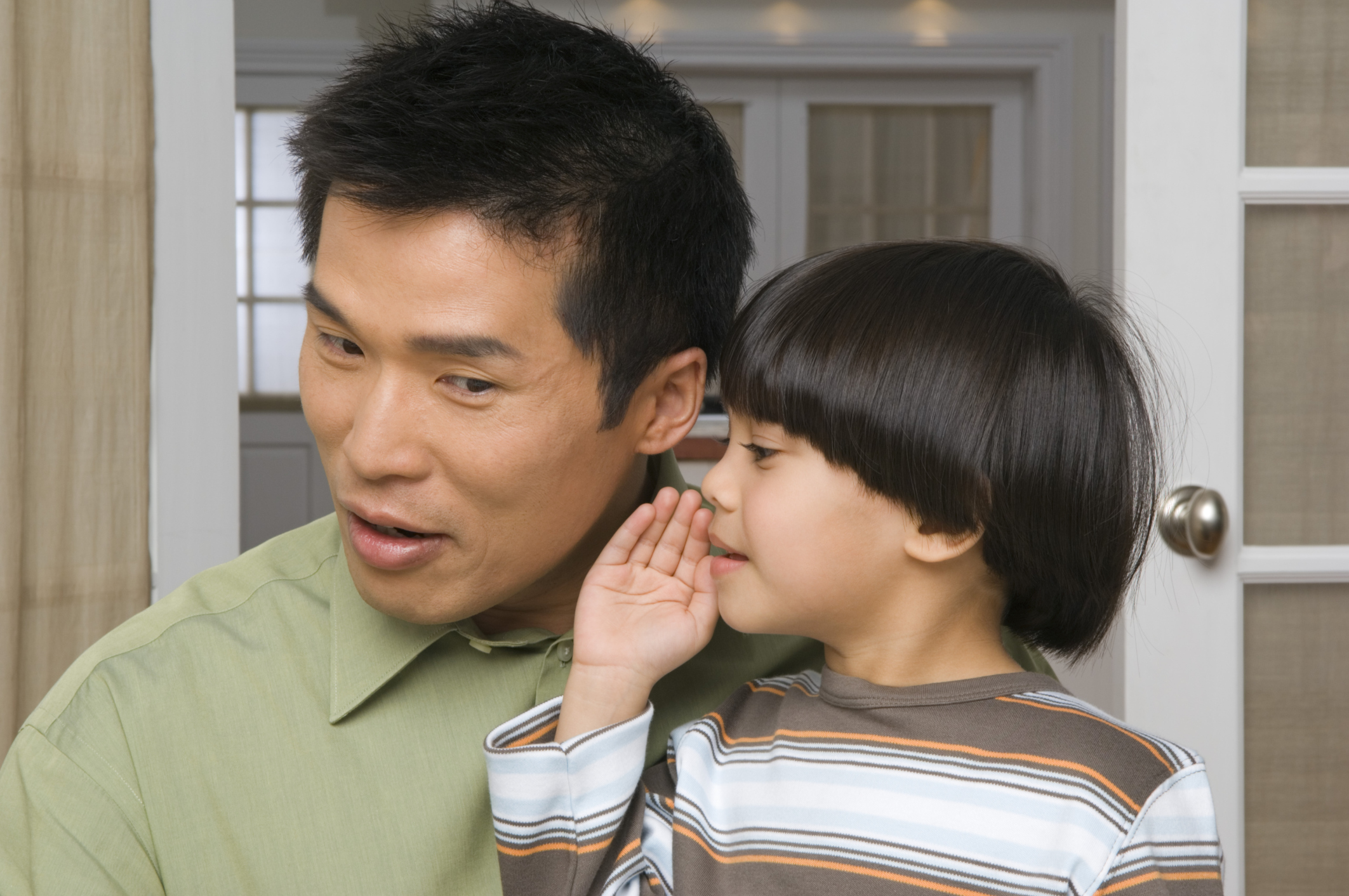 Son whispering into father's ear