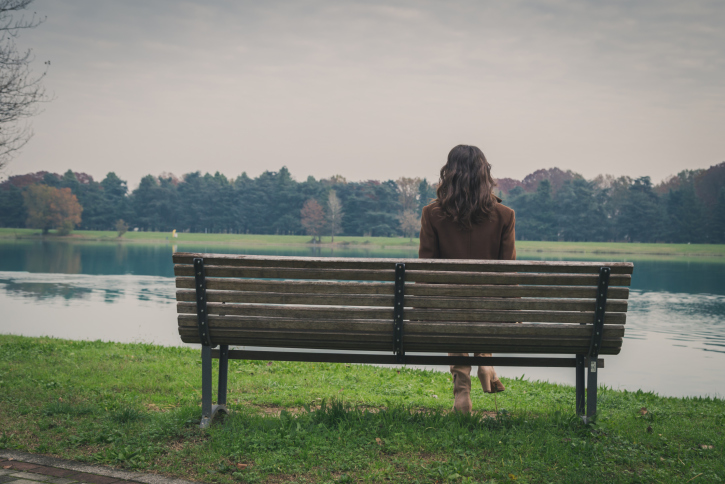 Young woman sitting on a bench in a city park