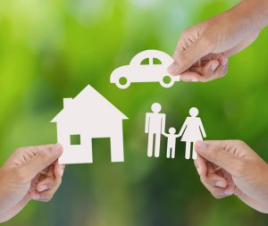 Hands holding up cutouts of a family, a house, and a car