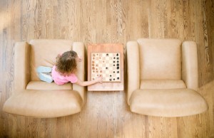 A girl plays chess alone next to empty chair